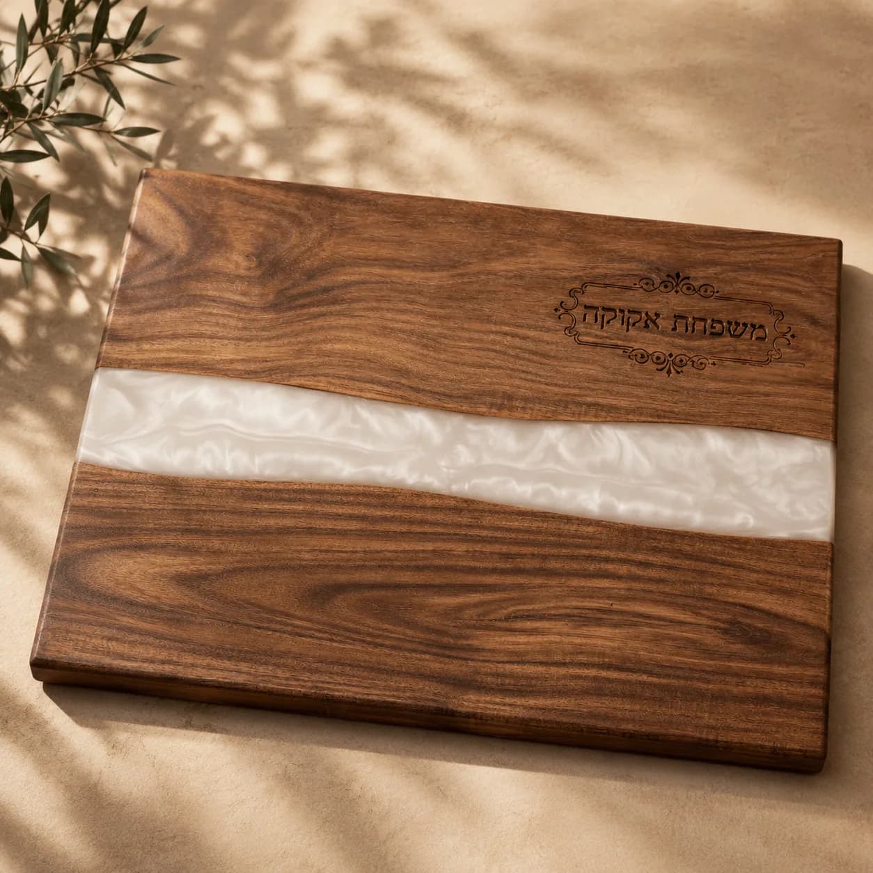 A walnut challah board with a river of white resin and a family name engraved on it.